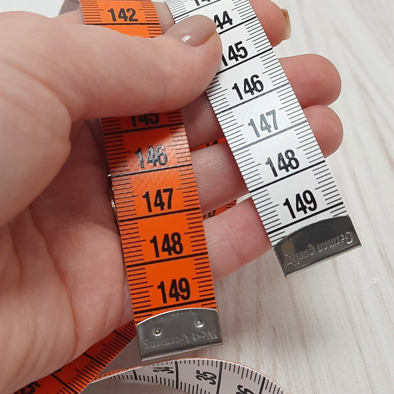 Сантиметрова стрічка помаранчево-біла з металевими накінечниками