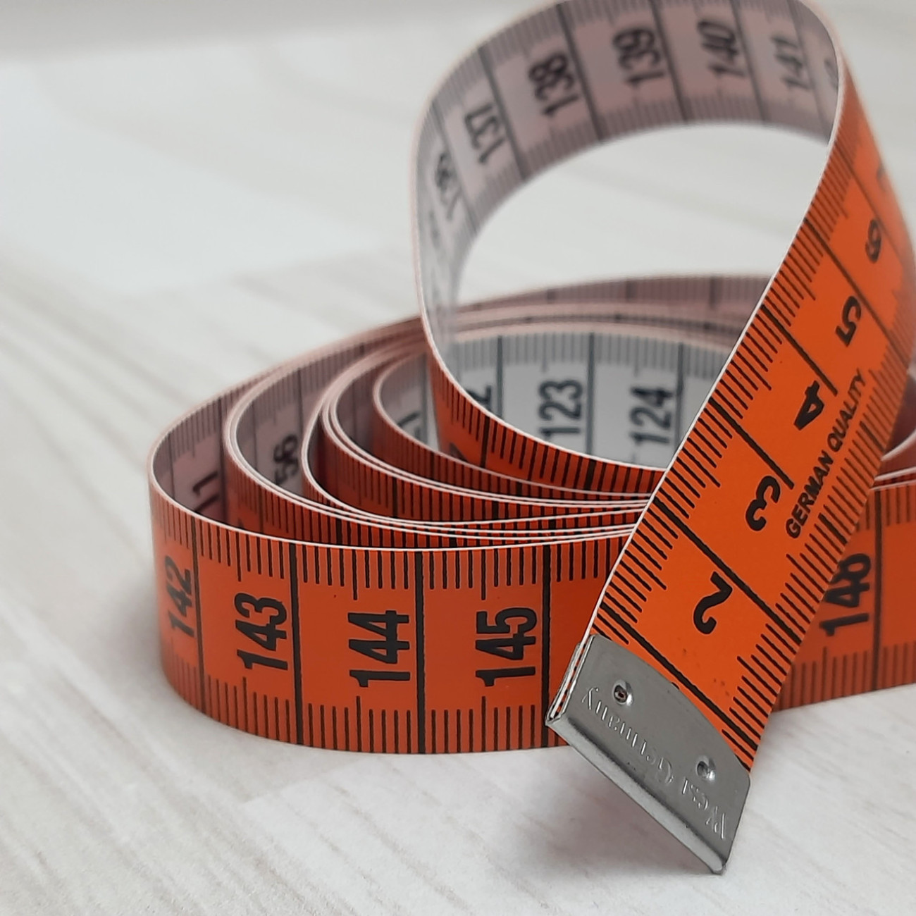 Сантиметрова стрічка помаранчево-біла з металевими накінечниками