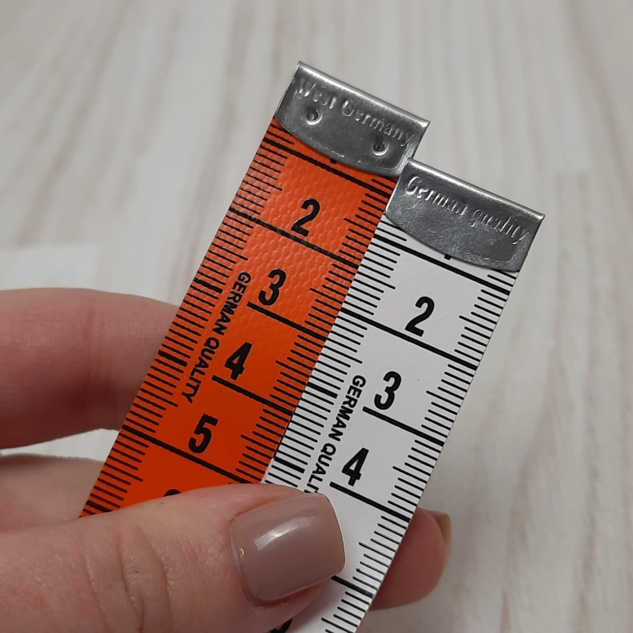 Сантиметрова стрічка помаранчево-біла з металевими накінечниками