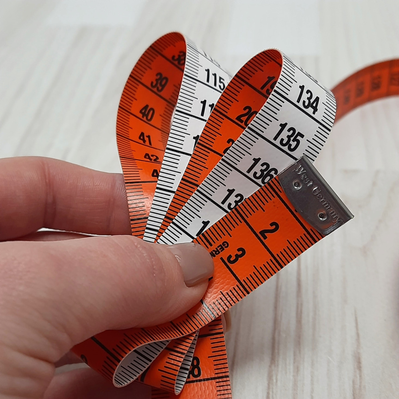 Сантиметрова стрічка помаранчево-біла з металевими накінечниками